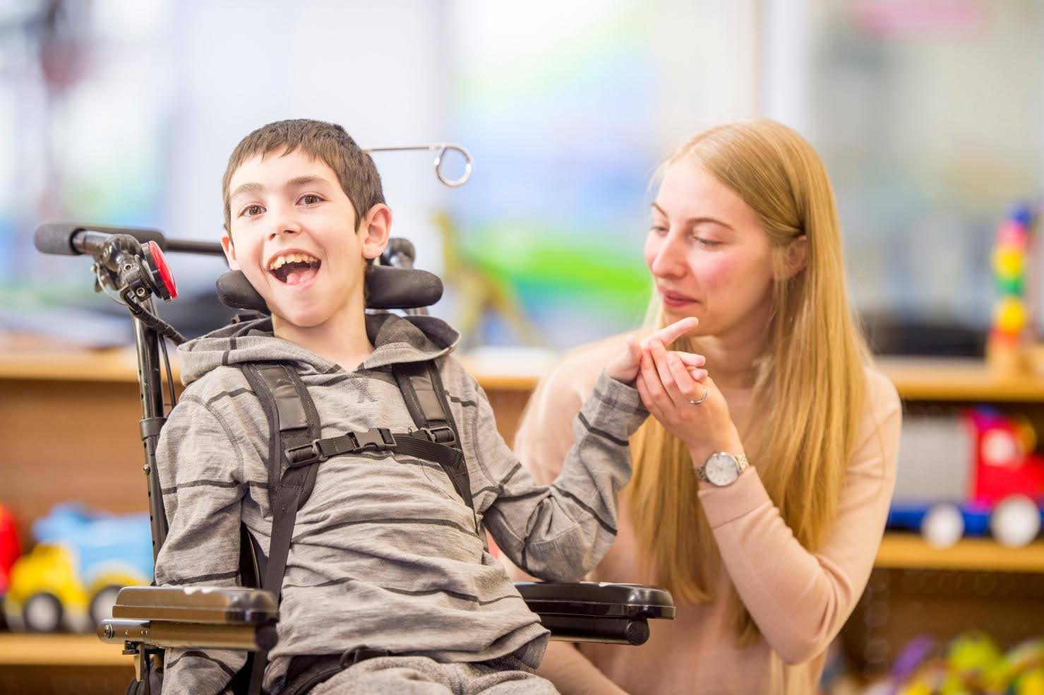 Caregiver supporting a smiling child with a disability, symbolizing strategies for improving staff retention and quality care in disability services.