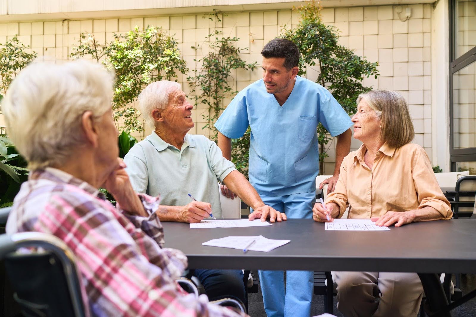 Caregiver interacting with seniors at a community center, illustrating common mistakes new senior centers make in daily operations and engagement.