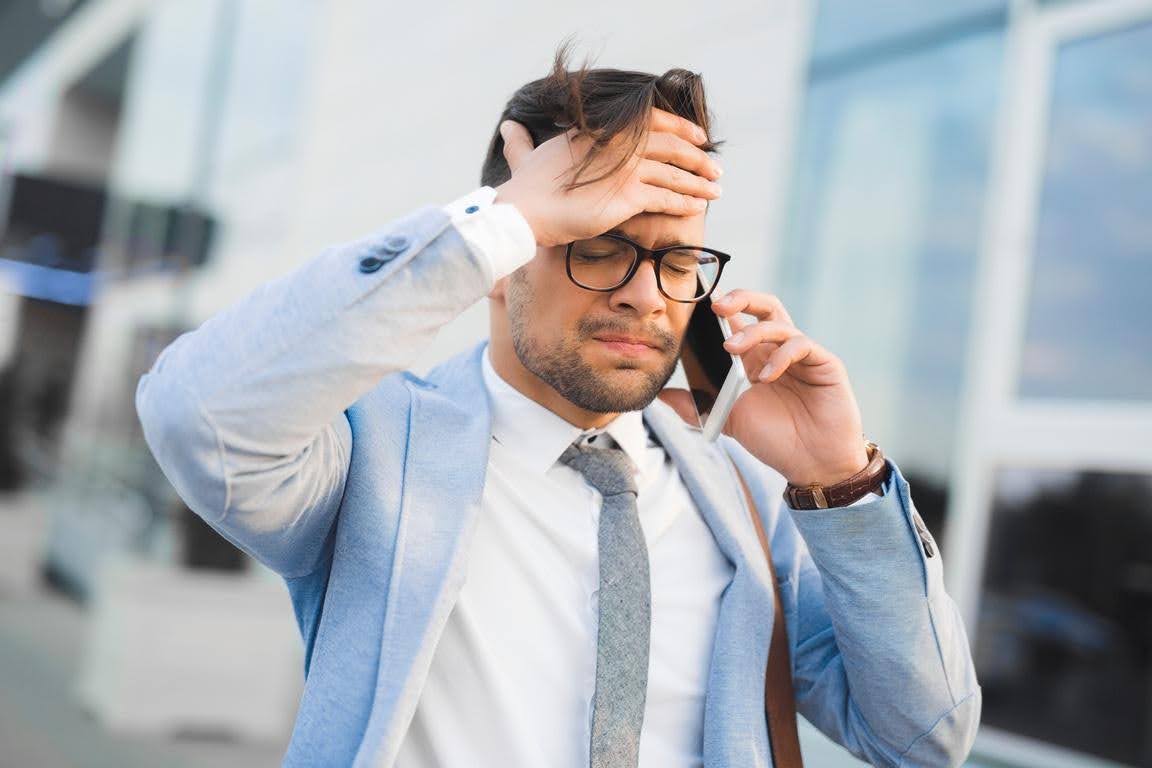Stressed manager handling a difficult call while facing staffing and management challenges in a healthcare business.