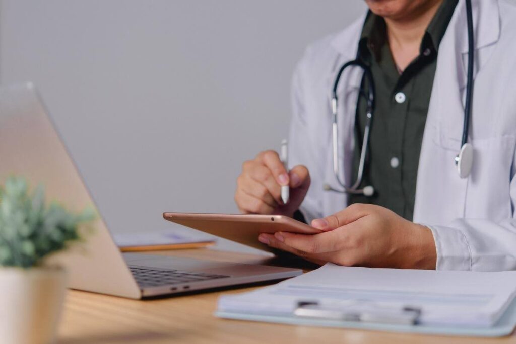 Healthcare professional reviewing digital records and compliance documentation on a tablet to identify potential regulatory issues before an inspection.