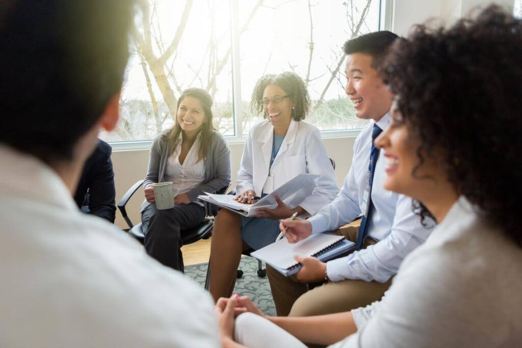 Healthcare professionals discussing business plans and reviewing documents during a team meeting, highlighting the importance of licensing preparation and service expansion for a healthcare business.