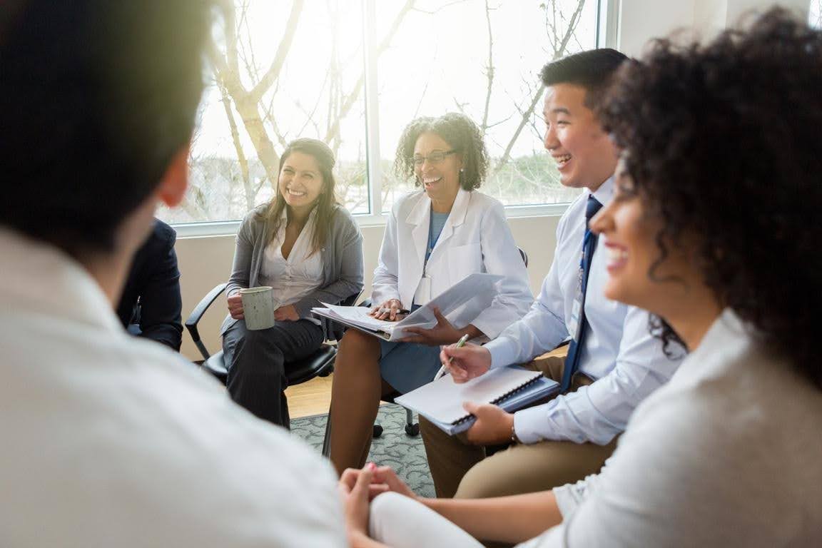 Healthcare professionals discussing business plans and reviewing documents during a team meeting, highlighting the importance of licensing preparation and service expansion for a healthcare business.