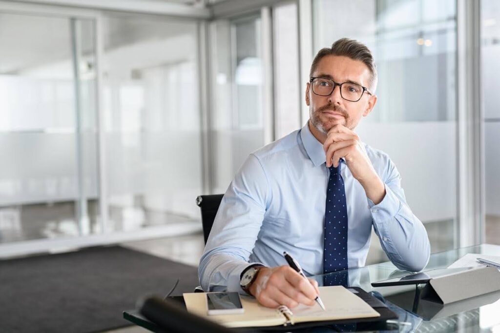 Thoughtful business owner reviewing notes at his desk, highlighting the challenges of managing healthcare business growth and improving operational processes.